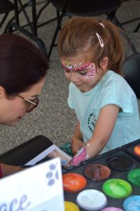 Child gets arm painted at Ride for Farley Community BBQ.